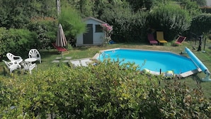 Un patio trasero con piscina, un cobertizo pequeño y mobiliario de exterior.