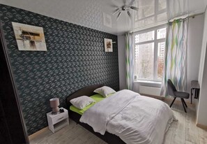 Relax in this serene bedroom with a large bed, comfortable chair, and a bedside table.