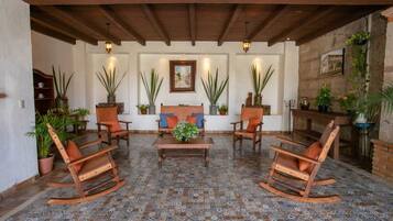 Un patio acogedor con mobiliario de madera, plantas en macetas y piso de baldosas.