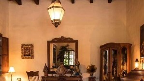 Un salon traditionnel avec une cheminée, un grand miroir et un meuble rempli d’objets décoratifs.