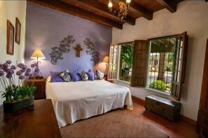 Relax in this serene bedroom with a large bed, two nightstands, and a window with a metal grill.