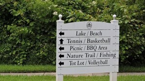 Un panneau de signalisation indiquant la direction à suivre pour accéder à différentes activités de loisirs, comme les courts de tennis, les aires de pique-nique, les sentiers de randonnée et les terrains de volley-ball.