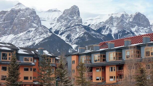 Un edificio de varios pisos con techo rojo, rodeado de montañas cubiertas de nieve.