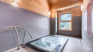Un cuarto de spa con jacuzzi, techo de madera y ventana con vistas.