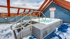 Un jacuzzi en un área exterior cubierta con una escalera metálica que lleva hacia él.