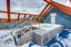 Un bain à remous situé dans un espace extérieur abrité, auquel on accède par un escalier en métal.