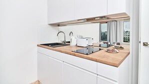 A modern kitchen with white cabinetry, a wooden countertop, a sink, a toaster, and a window with a city view.