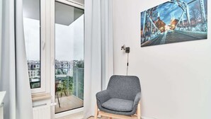 A modern room with a large window, a grey armchair, and a cityscape view.
