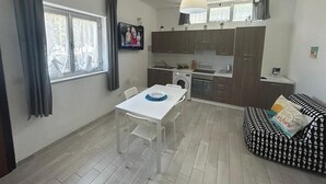 Une cuisine compacte avec un coin repas, un canapé et un téléviseur fixé au mur.