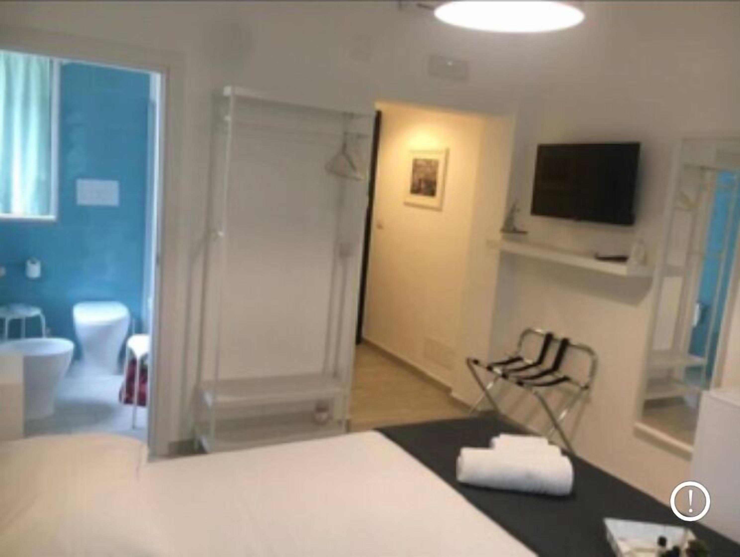 A hotel room with a bed, a TV, a shower, and a bathroom with a toilet and sink.