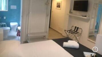 A hotel room with a bed, a TV, a shower, and a bathroom with a toilet and sink.