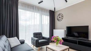 Ein modernes Wohnzimmer mit einer Couch, einem Sessel und einem Flachbildfernseher.