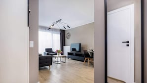 Ein modernes Wohnzimmer mit einer Couch, einem Couchtisch, einem Fernseher und einem Essbereich mit Stühlen.