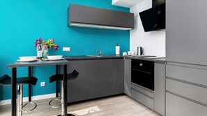 Una cocina moderna con paredes color turquesa, gabinetes grises y una campana extractora negra.