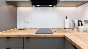 Une cuisine moderne avec un plan de travail en bois, une bouilloire en acier inoxydable, une tasse blanche et une planche à découper noire.