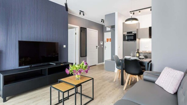 Un salon moderne doté d’un téléviseur à écran plat, d’un canapé, d’une table basse et d’un coin repas avec des chaises et une table.