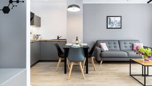 Une cuisine moderne avec des meubles gris, une table à manger avec des chaises, un canapé gris et un luminaire suspendu.