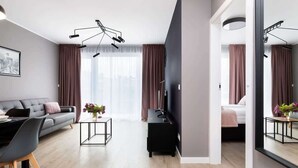Un salon moderne avec un canapé, une table basse et un téléviseur. Un grand miroir reflète l’ensemble de la pièce.