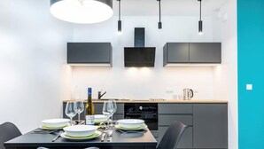 Una cocina moderna con armarios grises, horno empotrado y comedor con mesa dispuesta para dos.