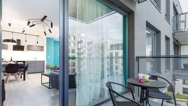 Un apartamento moderno con balcón, comedor y cocina con vista a la ciudad.
