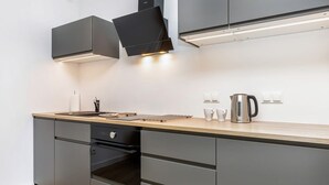 Una cocina moderna con armarios grises, encimera de madera y electrodomésticos de acero inoxidable.