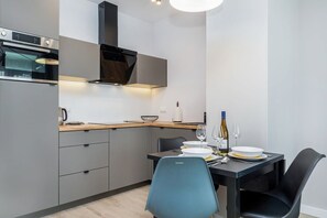 Una cocina moderna con armarios grises, una estufa negra y un comedor con una mesa y sillas negras.