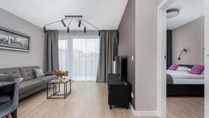 Un salon moderne comprenant un canapé, une table basse, un meuble pour la télévision et un lit donnant sur un paysage urbain.