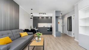 Una sala de estar moderna con un sofá gris, una mesa de centro y una cocina al fondo.