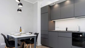 Una cocina moderna con gabinetes grises, una encimera blanca y un comedor con mesa dispuesta para cuatro.