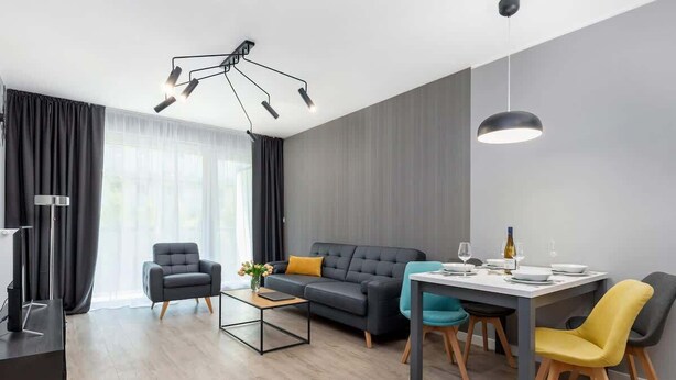 A modern living room with a sofa, armchairs, a dining table, and a TV.