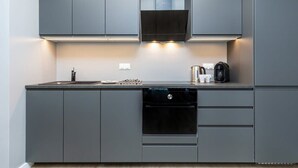 A modern kitchen with grey cabinetry, a built-in oven, and a coffee maker on the countertop.