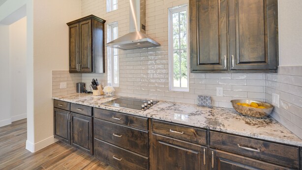 A kitchen with dark wooden cabinets, white subway tiles, and a granite countertop. - 'Cascada at Canyon Lake' ~ 1 Mi to Wedding Venues! (Spring Branch)