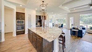 A spacious kitchen with a large island, built-in appliances, and a dining area with a blue sofa and chairs. - 'Cascada at Canyon Lake' ~ 1 Mi to Wedding Venues! (Spring Branch)