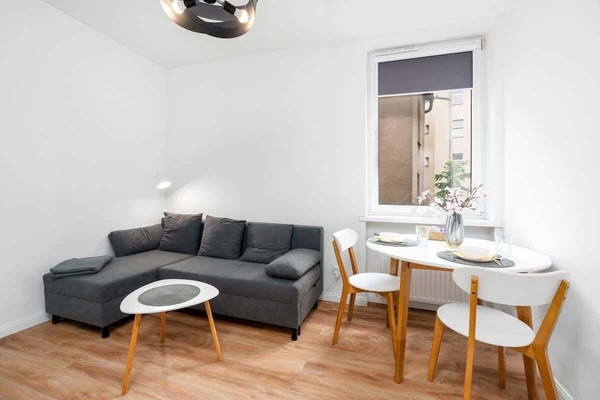 A cozy living room with a gray sofa, a small round coffee table, and light-colored wooden flooring.
