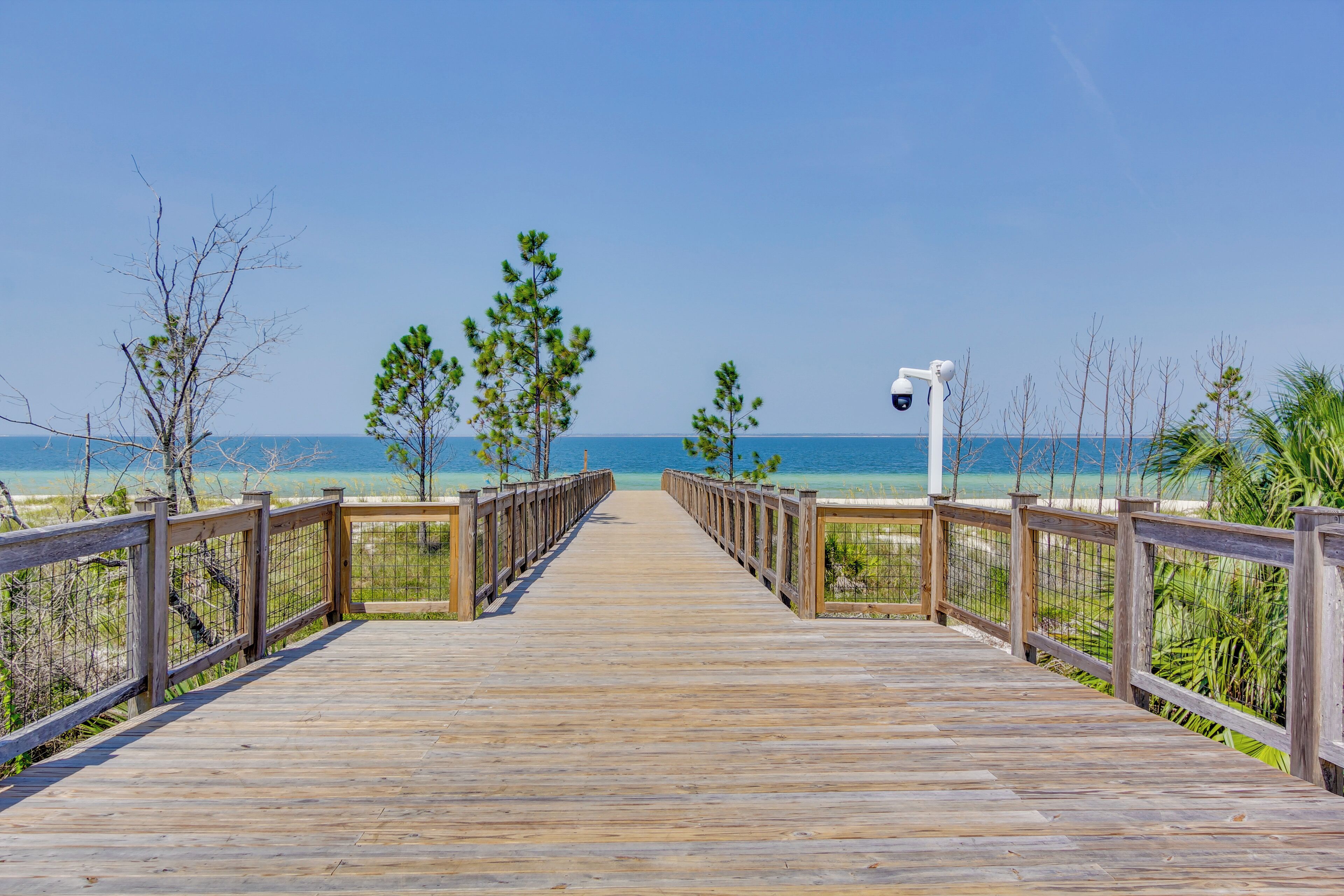 A wooden boardwalk leading to a beach with clear skies.