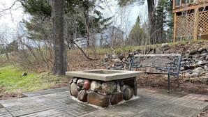 Un hogar de piedra con un banco de metal en un entorno natural.