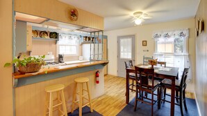 A kitchen with a wooden counter, stools, and a dining table with chairs. - Carolina Country Cabin! Hot Springs Getaway (Hot Springs)