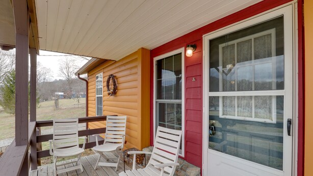 A porch with two white Adirondack chairs, a wooden railing, and a door with a glass panel. - Carolina Country Cabin! Hot Springs Getaway (Hot Springs)