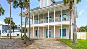 A two-story building with a balcony, surrounded by palm trees. - Southern Jewel  - Vacation Home Near the Beach with Private Pool & Outdoor Space (Destin)
