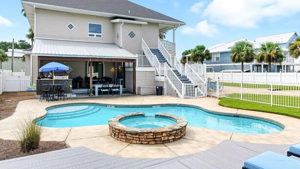 A two-story house with a covered patio, a swimming pool with a hot tub, and a fenced backyard. - Southern Jewel  - Vacation Home Near the Beach with Private Pool & Outdoor Space (Destin)
