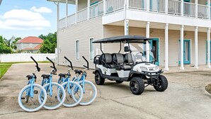 A building with a porch, a golf cart, and four bicycles parked in front. - Southern Jewel  - Vacation Home Near the Beach with Private Pool & Outdoor Space (Destin)
