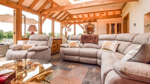 Una sala de estar acogedora con un sofá modular, una mesa de centro de cristal y vigas de madera en el techo.