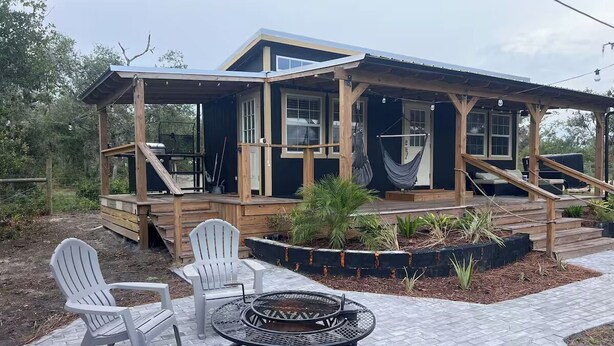 A wooden deck with Adirondack chairs and a fire pit. - Lake Side Tiny home in Punta Gorda, Florida (Punta Gorda)