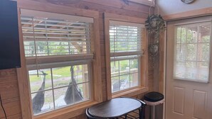 A room with wooden walls, a round table with two chairs, a trash bin, and a door with a window. - Lake Side Tiny home in Punta Gorda, Florida (Punta Gorda)