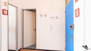 Ein Flur mit einer blauen Tür, einer weißen Tür und einer geschlossenen Tür. Wandschlüssel und ein Telefon sind angebracht.