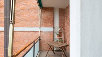 Un balcon avec une table en bois et une étagère en métal où sont disposées des plantes en pot.