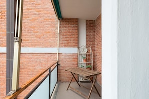 Un balcon avec une table en bois et une étagère en métal où sont disposées des plantes en pot.