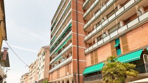 Ein mehrstöckiges Hotel mit Balkonen, einer grünen Markise und einer Palme im Vordergrund.
