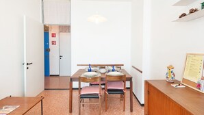 Ein Essbereich mit Tisch für vier Personen, einem Holzschrank und einer Pinwand mit Unterlagen.