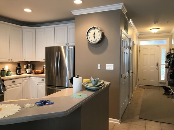 A modern kitchen with white cabinets, stainless steel appliances, and a central island.